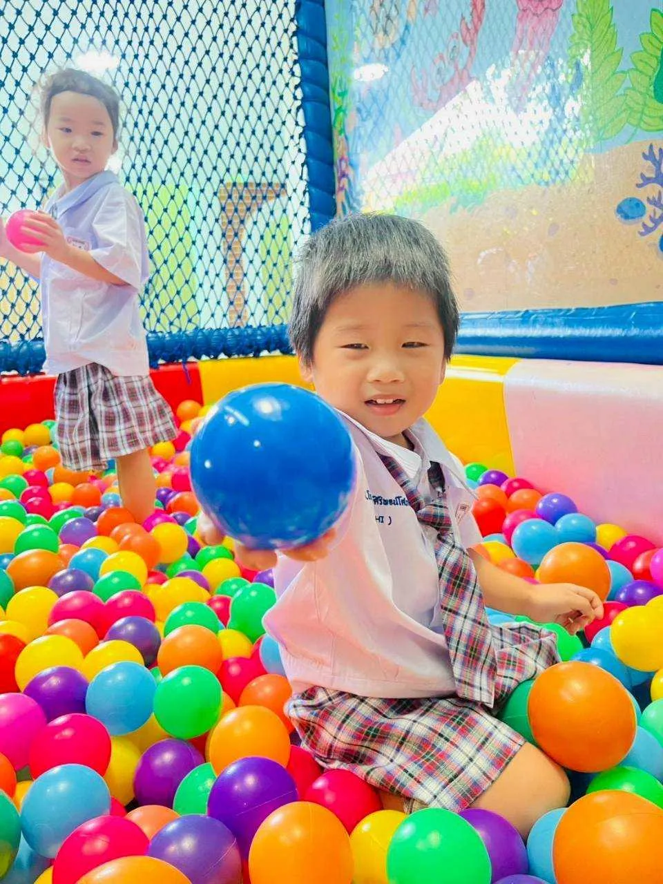 Child playing joyfully in the colourful ball pit