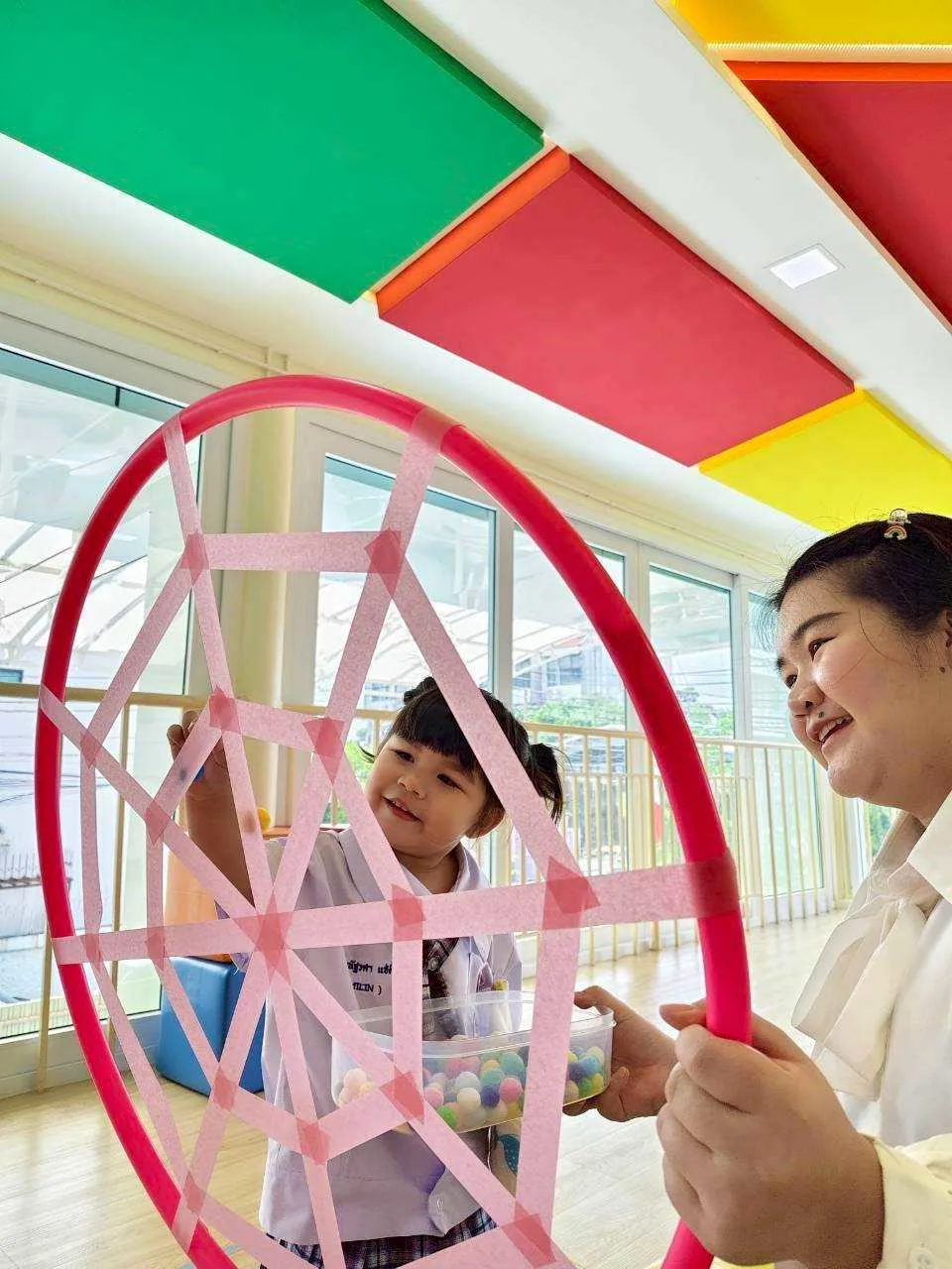 Child threading beads on a hoop in a bright classroom