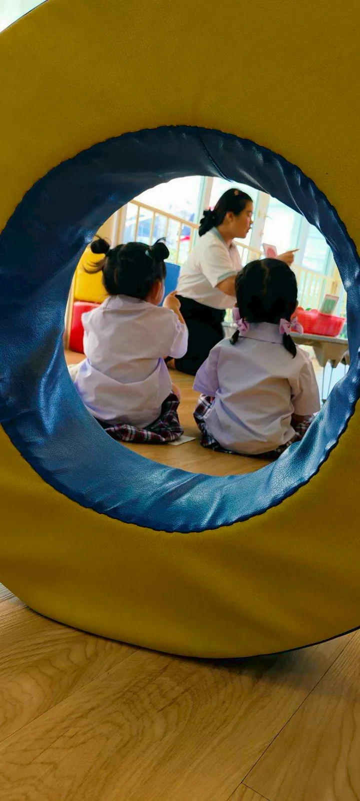Child peeking through a soft sensory play tunnel