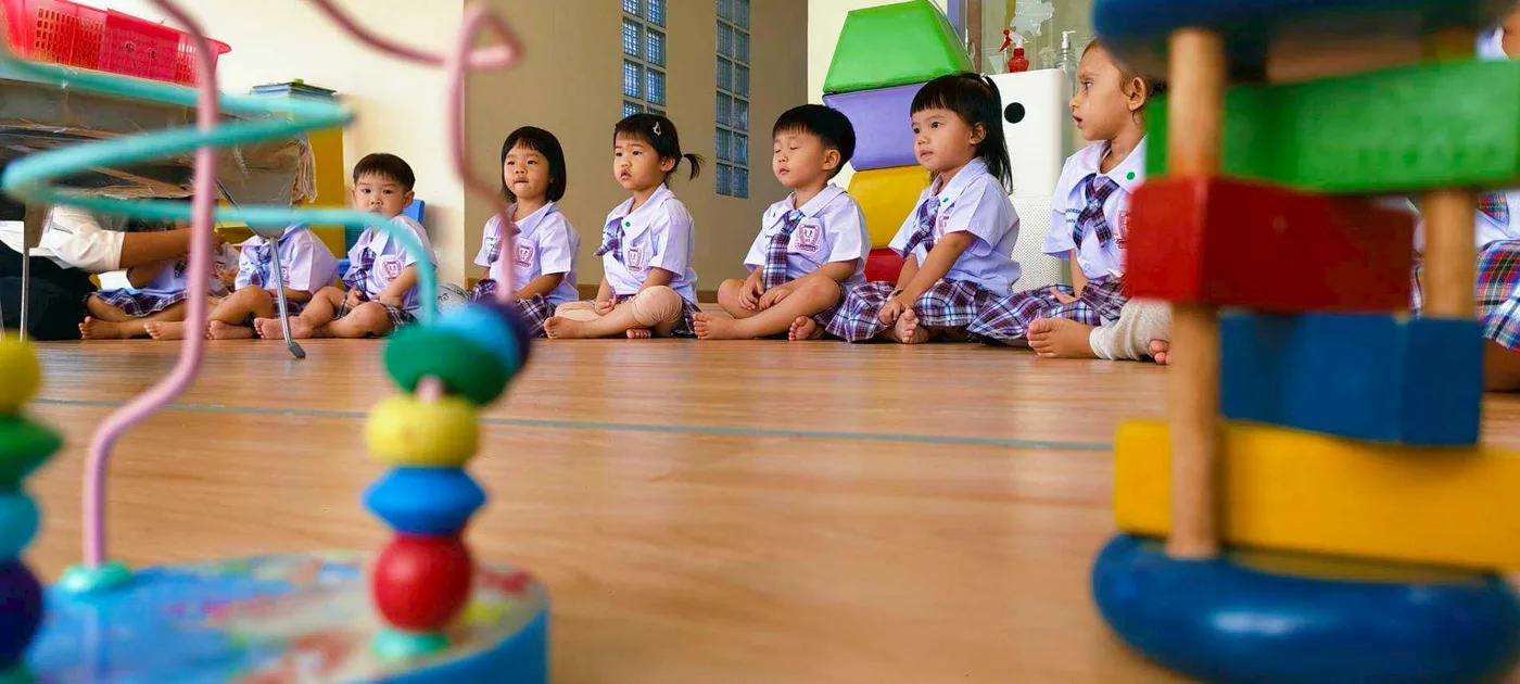 Children exploring a bead and button sorting tray with the teacher